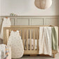 Cot fitted sheets, cream woodland print on bed with fitted corners visible