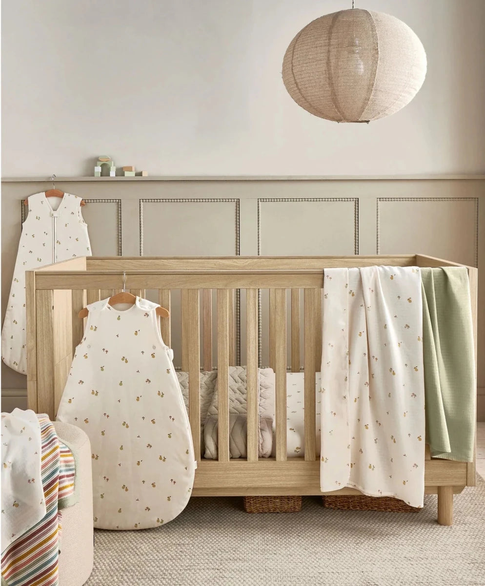 Cot fitted sheets, cream woodland print on bed with fitted corners visible