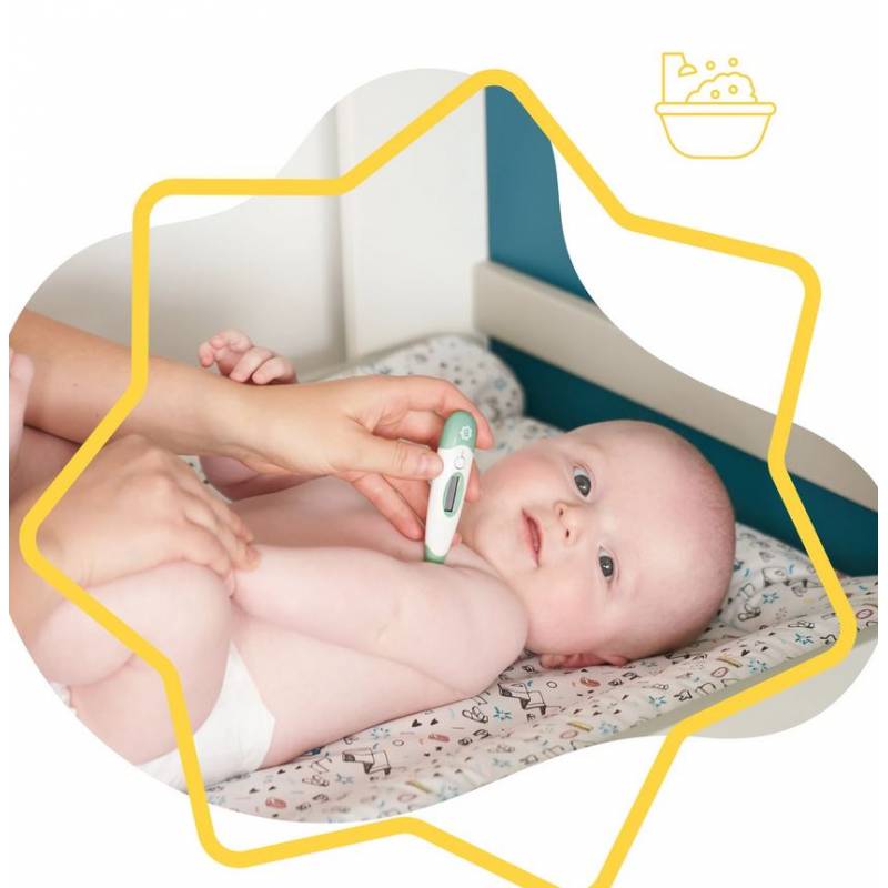 Green digital thermometer held by a hand next to a baby