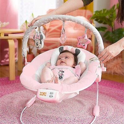 Pink Minnie Mouse baby bouncer with hanging toys, baby lying in the seat