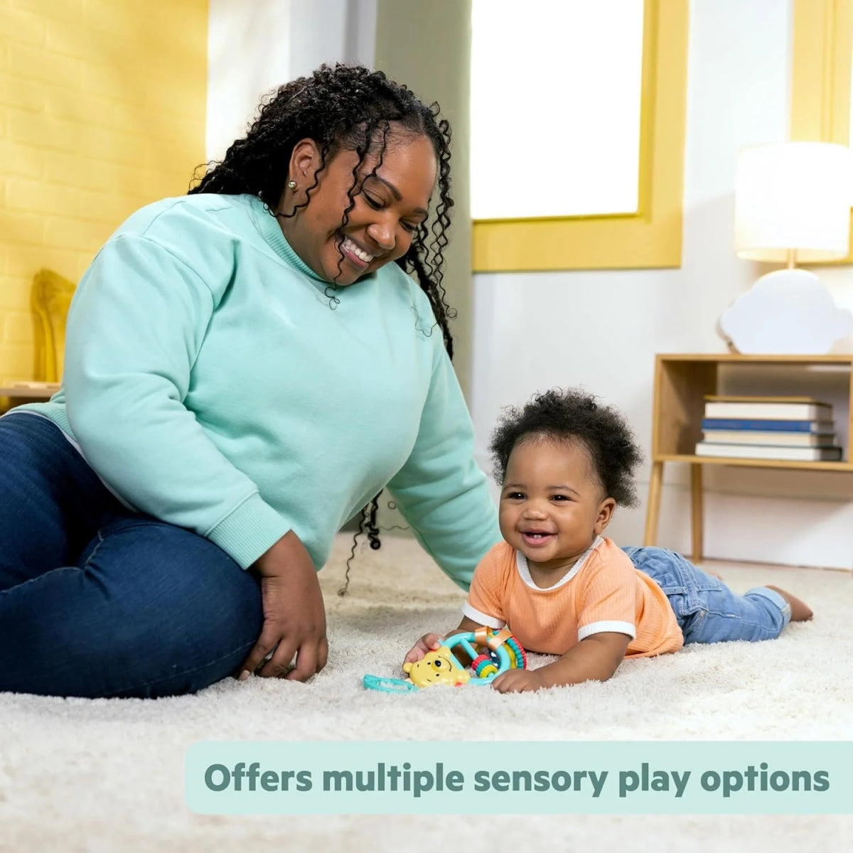 Winnie the Pooh stroller activity toy with teal rings and colorful rattle pieces on carpet