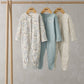 Set of 3 footed sleepsuits on a hanger: white floral print, blue solid, cream with tiny motifs