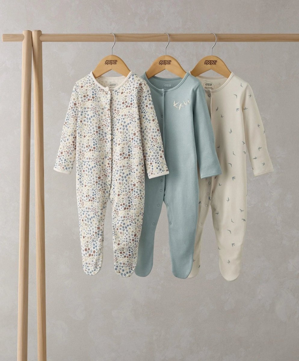 Set of 3 footed sleepsuits on a hanger: white floral print, blue solid, cream with tiny motifs