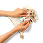 Cream plush dog dummy holder with hands inserting pacifier into the toy pocket
