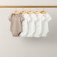5-pack baby bodysuits on hanger: one taupe and four white with small tree prints