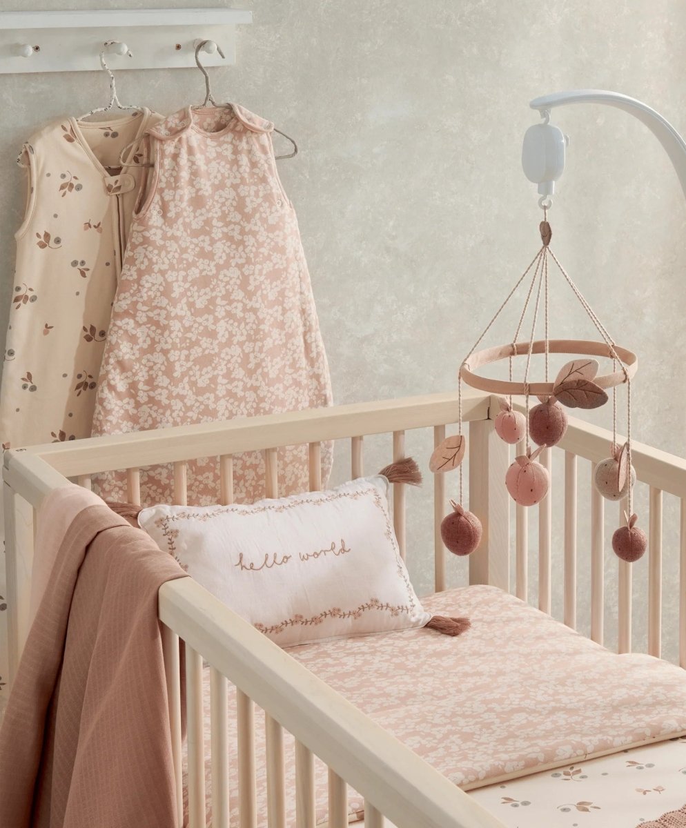 Peach floral sleeveless baby sleep bag on crib mattress, sleeveless with pink trim