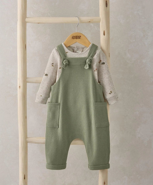 Green dungarees with adjustable bow straps over speckled long-sleeve bodysuit