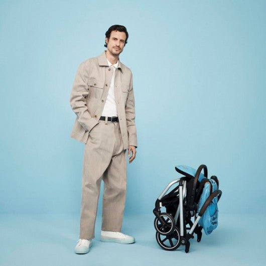 Dark stroller with blue accents and canopy, standing beside a person