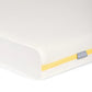 Cotbed mattress corner close-up, white cover with yellow piping