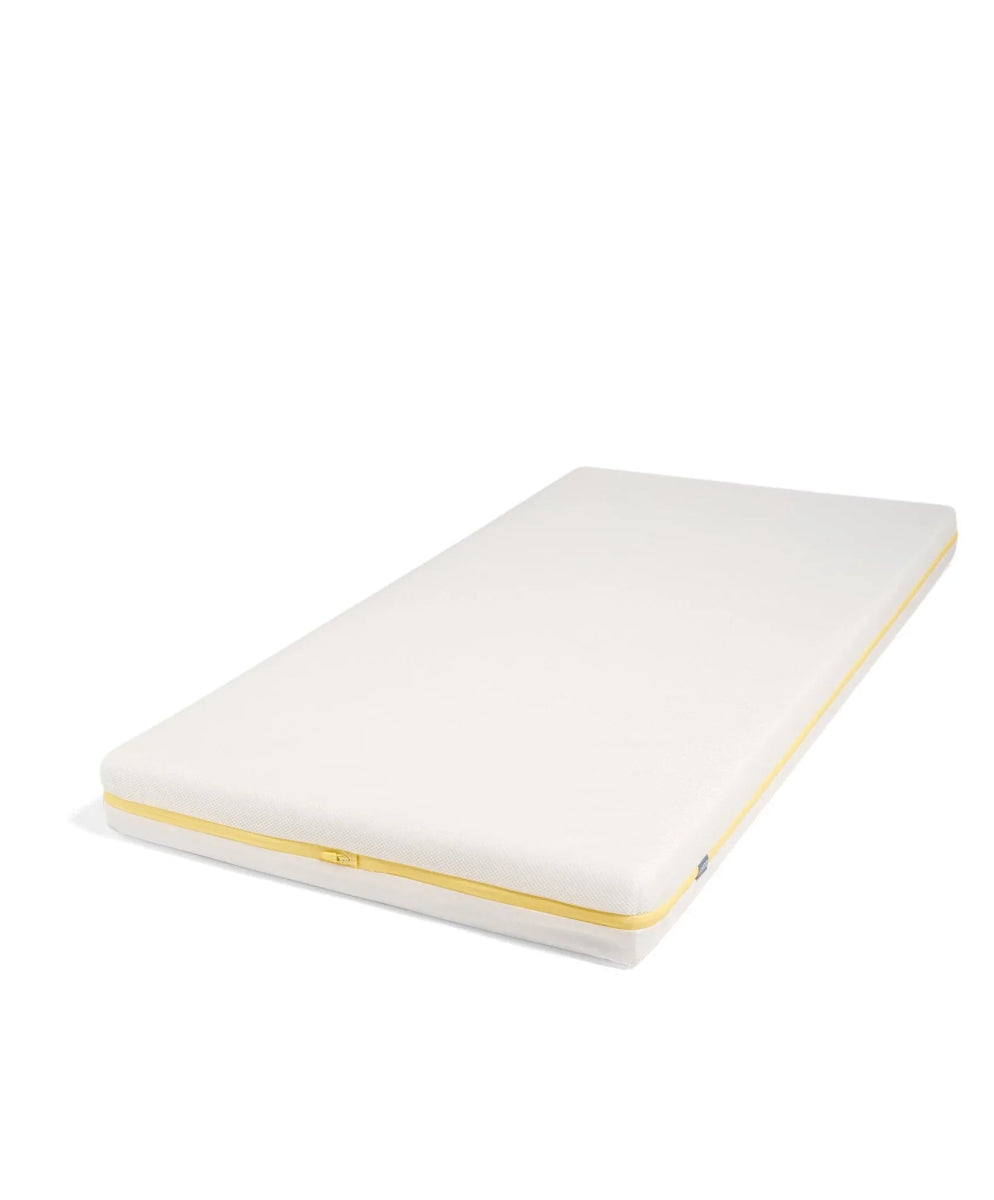 Cotbed mattress with white cover and yellow edge piping, flat top view