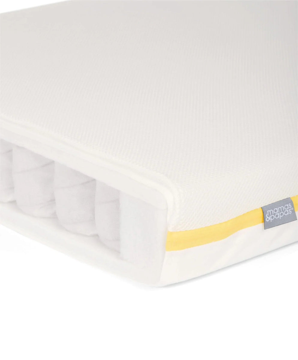Cotbed mattress with white cover and yellow edge piping, side view