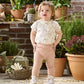 Floral baby bodysuit with short sleeves and round neckline, paired with pink pants
