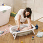Foldable baby bathtub in a bathroom with a baby being washed, white rim and light blue tub