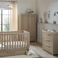 Oak-toned cot bed with slatted sides beside matching dresser changer and drawers