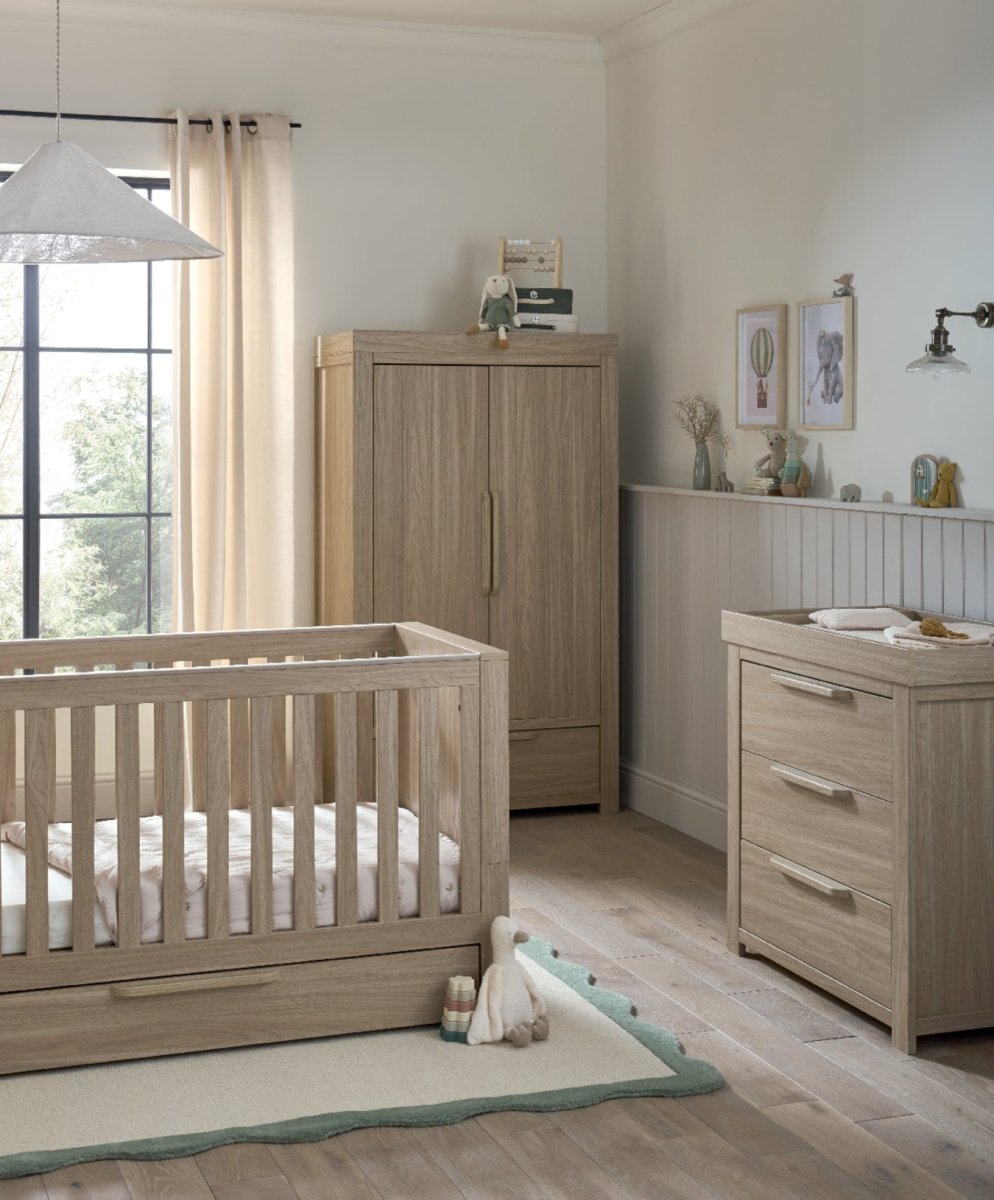 Oak-toned cot bed with slatted sides beside matching dresser changer and drawers