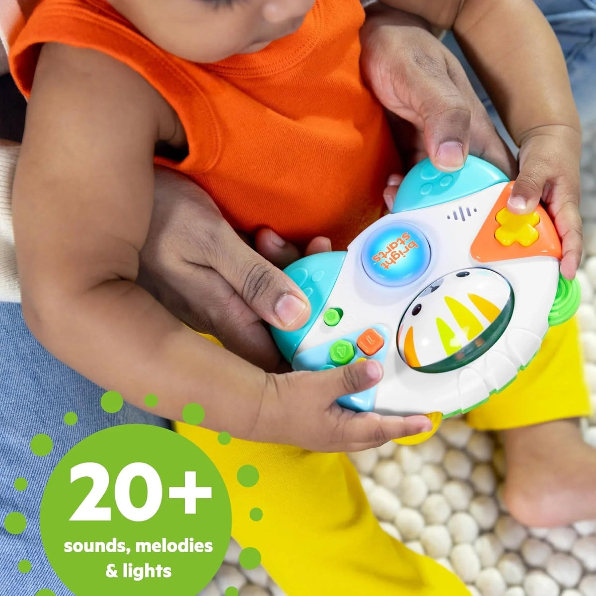 Baby hands holding tiger-faced game controller toy with buttons and glowing center