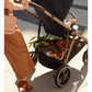 Black stroller with handlebar and front basket holding stored items, side view