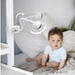 White baby video monitor camera with clip mount and cable, aimed toward a crib