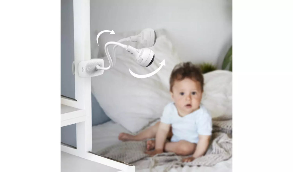 White baby video monitor camera with clip mount and cable, aimed toward a crib