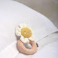 Flower grabber ring rattle toy with white petals, tan ring, yellow smiling face