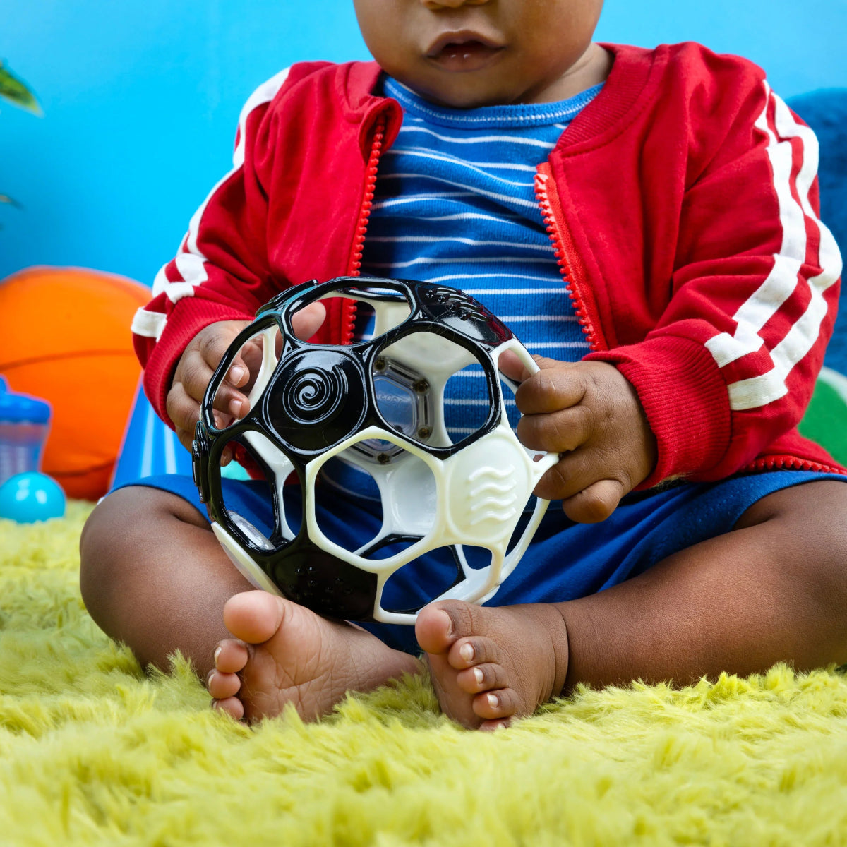 Black and white soccer rattle ball with colorful rattle window held in hands