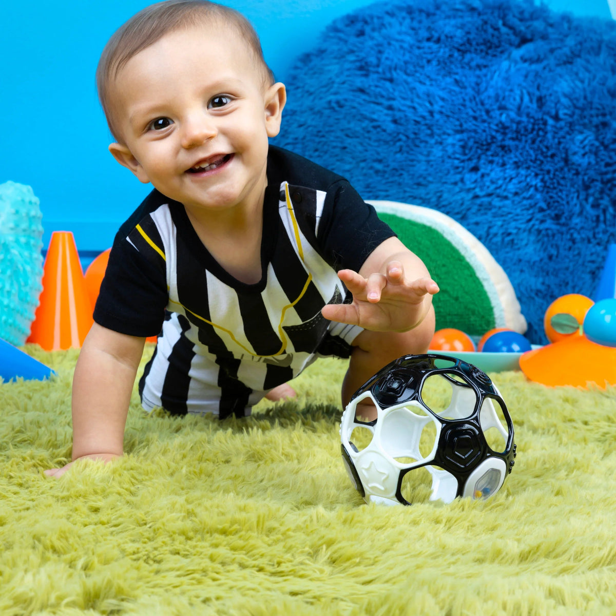 Black and white soccer rattle ball with colorful rattle window on play floor