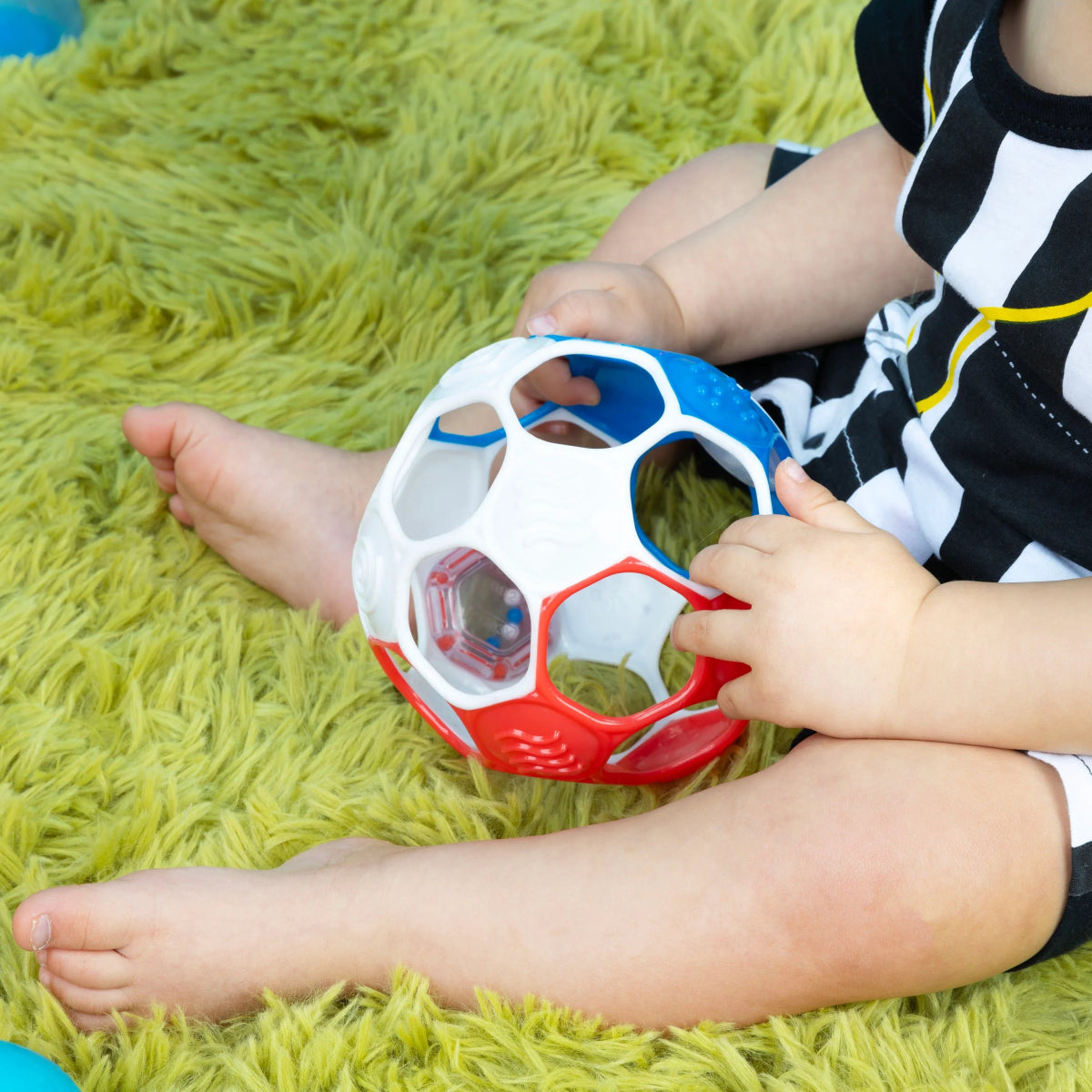 Red, white, and blue rattle soccer ball grasped by a child’s hands