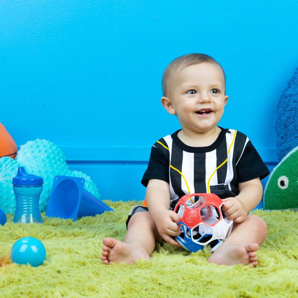 Red, white, and blue rattle soccer ball held by a sitting baby
