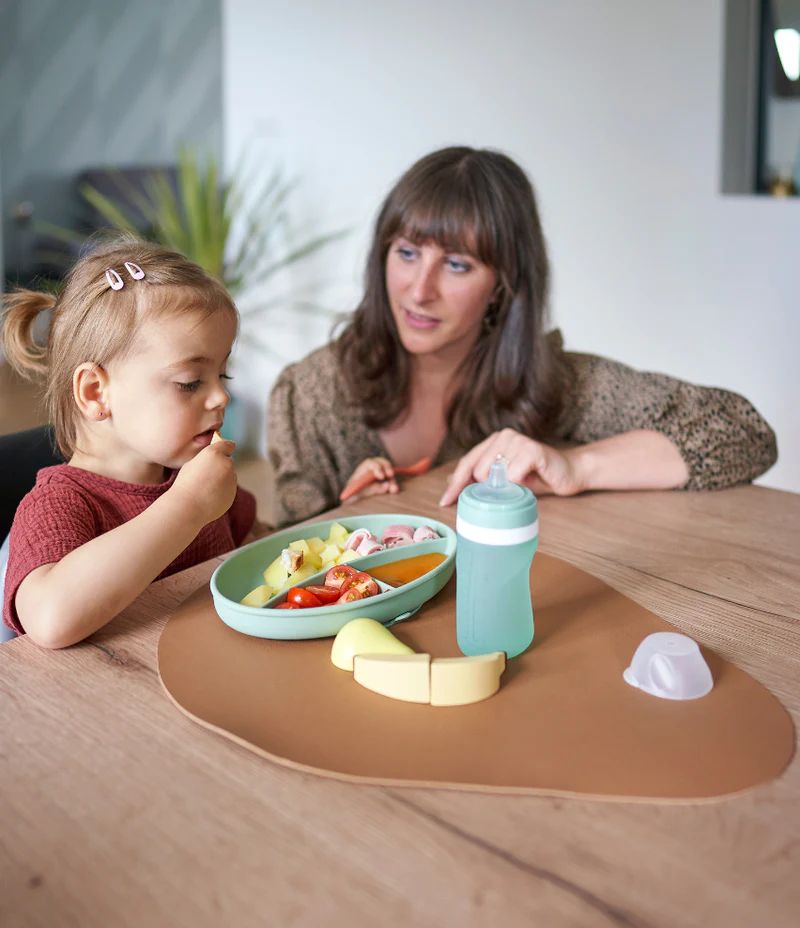 Silicone feeding bowl set with mint bottle and feeding spoons on table