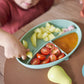 Silicone feeding bowl with compartments and orange spoon holding vegetables
