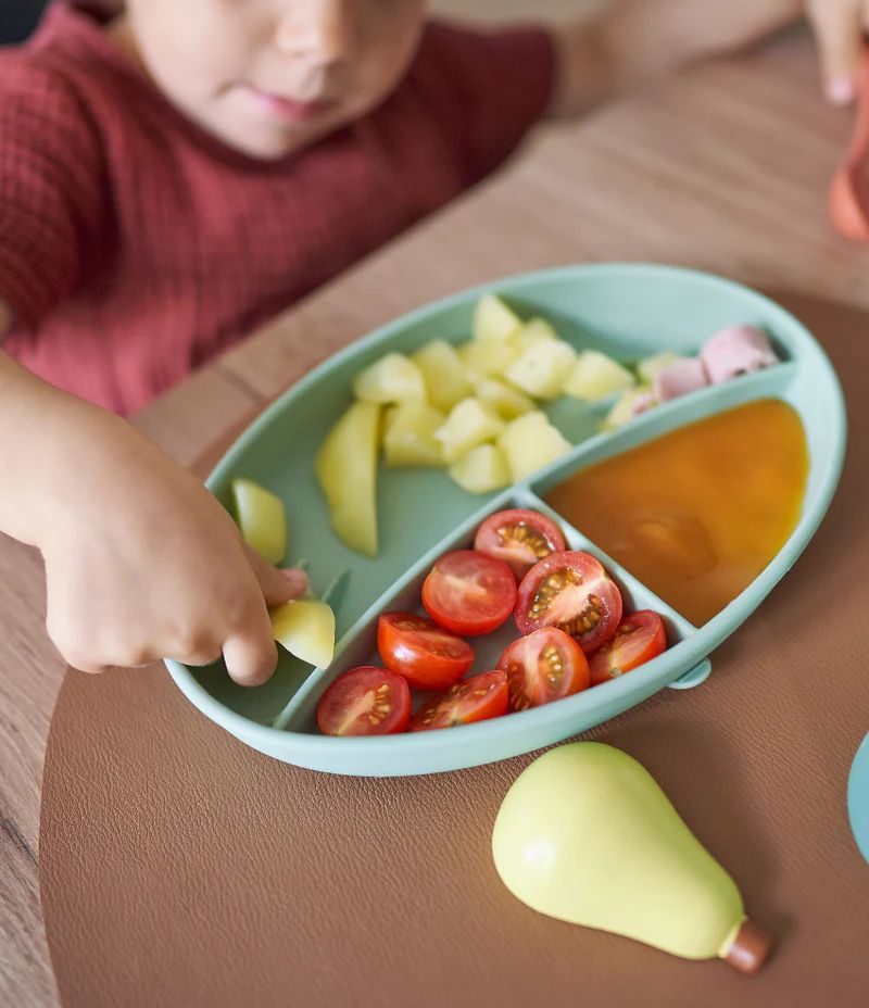 Silicone feeding bowl with compartments and orange spoon holding vegetables