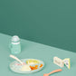 Silicone feeding bowl with spoon and mint baby bottle on table