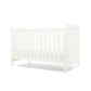 White cotbed with vertical slat sides and paneled headboard, toddler bed ready design