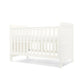 White cotbed with paneled end board and tall slat headboard, front three-quarter view
