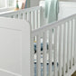 White cotbed with slatted rails and mattress, end panel and posts visible