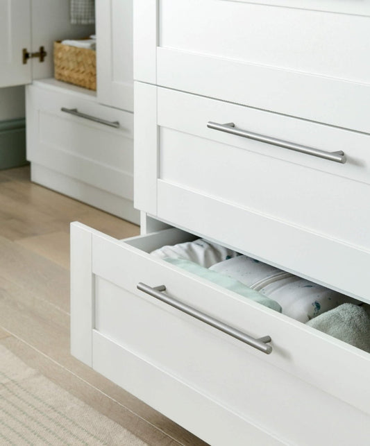 White nursery dresser changer with metal bar pulls and open drawer