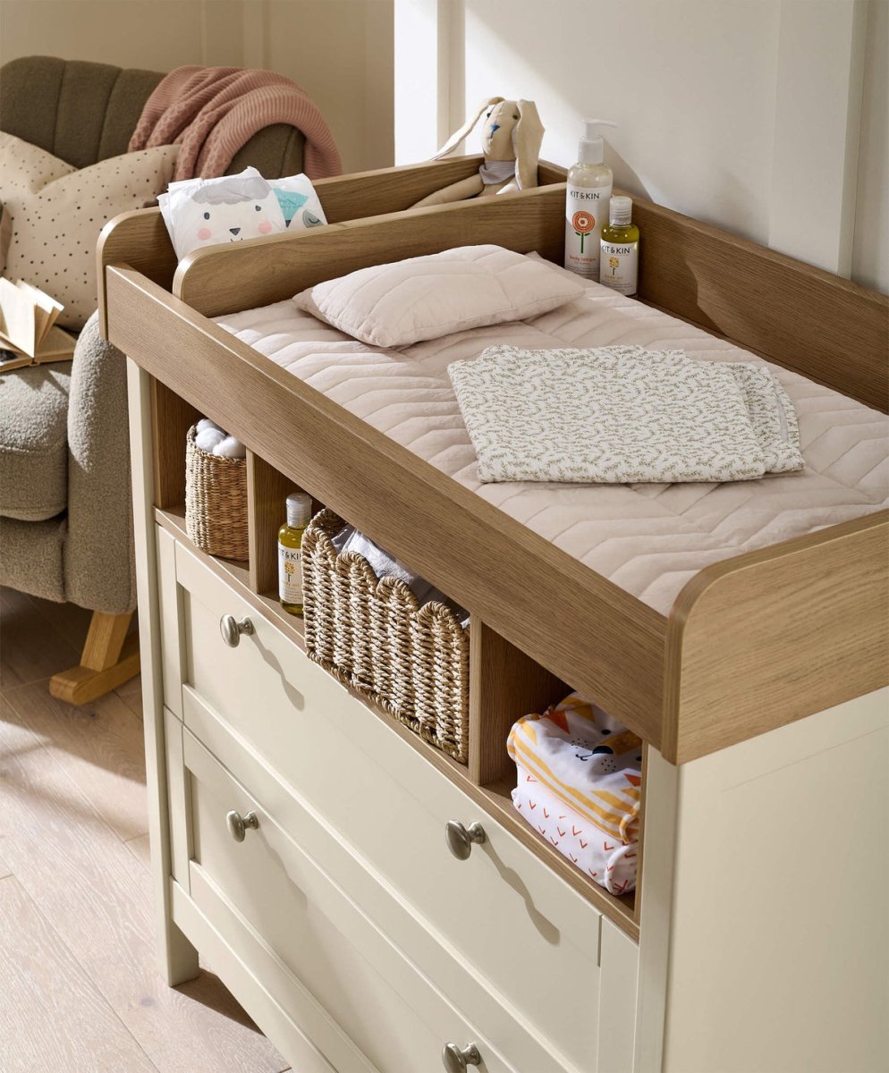 Baby dresser changer with cushioned changing surface and side rails, white drawers