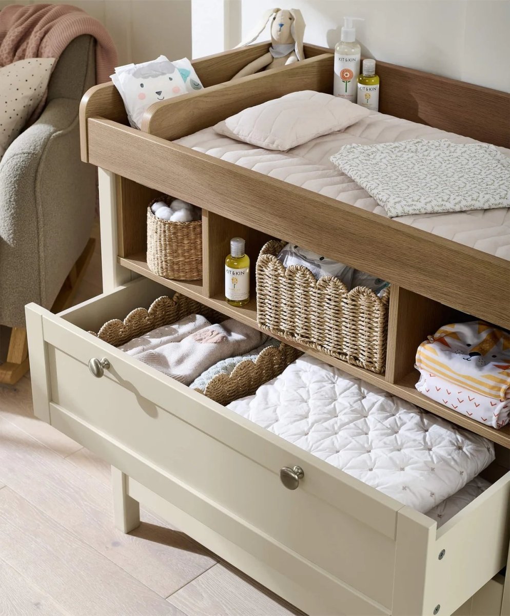 Baby changing dresser with open top shelf and lower drawers, light cream frame