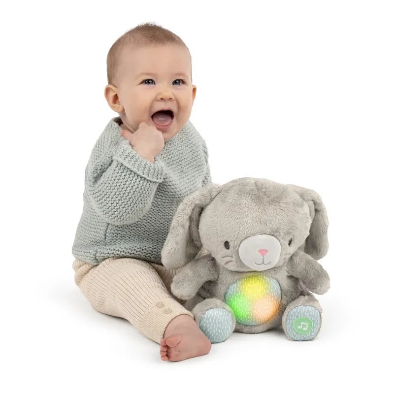 Grey plush bunny soothing toy with glowing belly lights, held by a baby