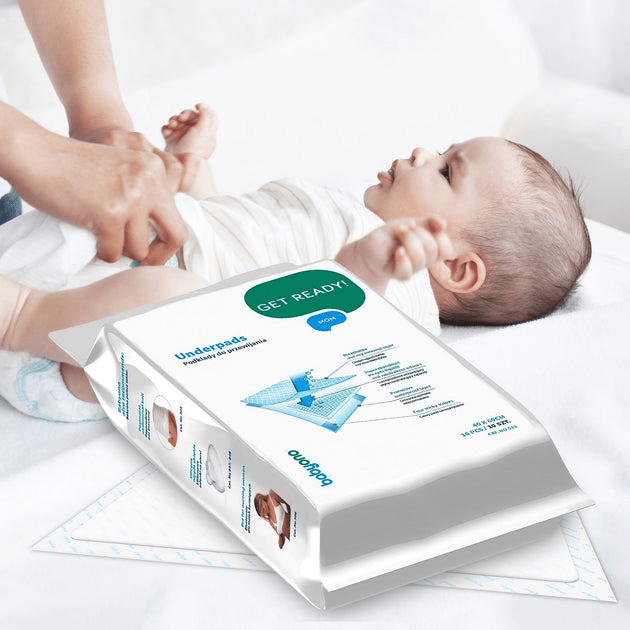 Hygienic underpad sheet on bed with care pack beside it