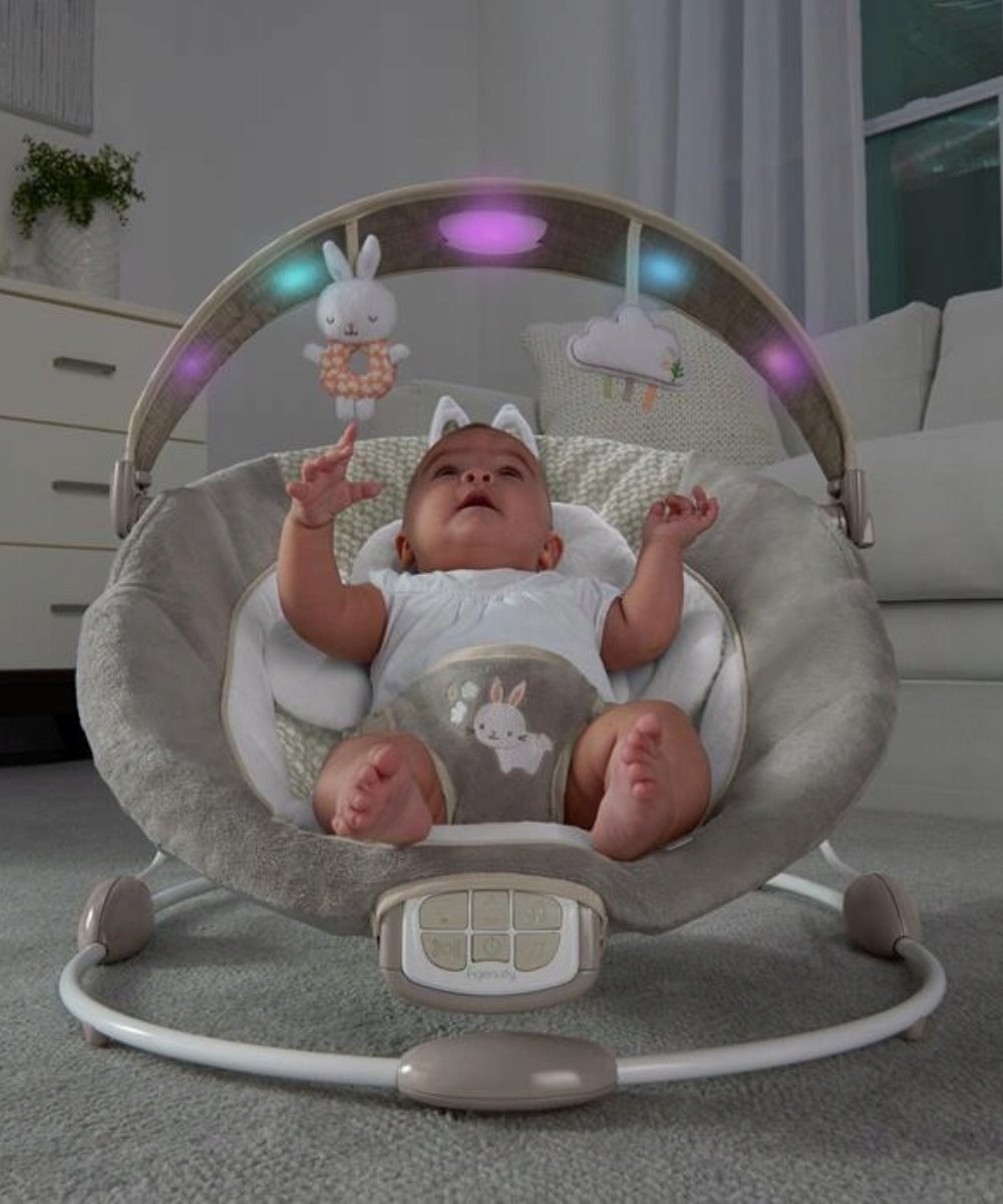 Infant bouncer with LED toy arch, grey seat, and bunny and cloud plush toys