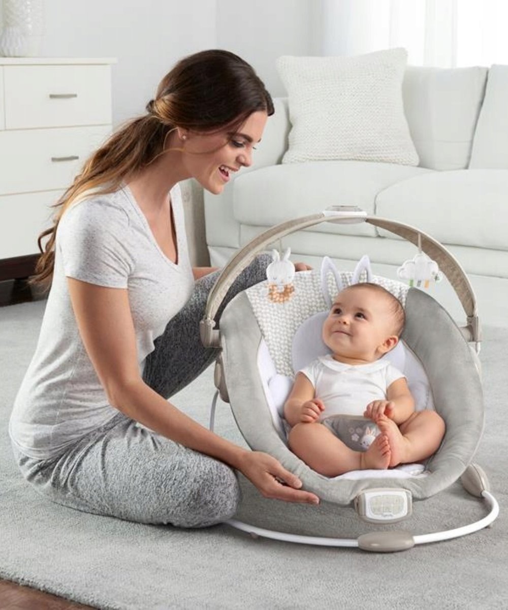 Infant bouncer with grey seat and plush bunny toy arch