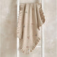 Cream knitted blanket folded with ruffled border and small multicolor motifs
