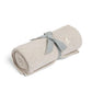 Light grey knitted blanket, rolled with blue fabric tie.