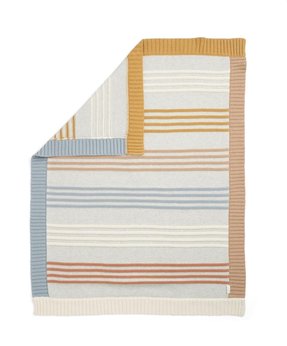 Knitted striped blanket folded over, featuring tan, cream, blue, and rust stripes