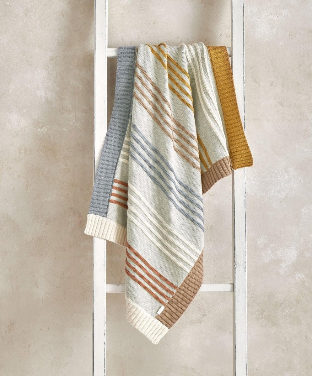 Knitted striped blanket with blue, cream, and rust stripes, ribbed border