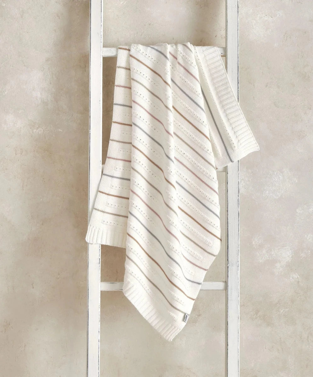 Cream knitted throw blanket with thin neutral stripe lines, folded over