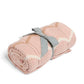 Pink knitted wave blanket rolled with gray fabric strap and cream zigzag stripes