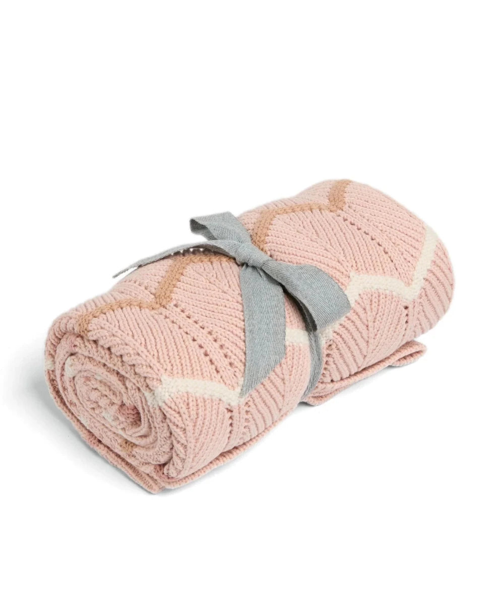 Pink knitted wave blanket rolled with gray fabric strap and cream zigzag stripes
