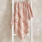 Pink knitted wave blanket draped with white zigzag knit pattern, squared corner